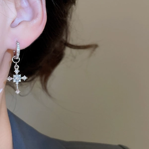 Close-up of sparkling silver cross earrings with zircons on a model for everyday wear