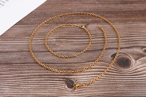 Flat lay of delicate 18k gold-plated titanium steel chain set on a rustic wooden surface