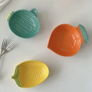 Set of cute ceramic sauce dishes in cactus, carrot, and corn shapes on white background
