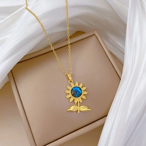 Détail du pendentif tournesol avec pierre bleue et feuilles dorées sur soie