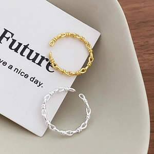 S925 silver braided knot chain rings in gold and silver finish on ceramic display
