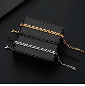 Detailed view of gold, black and silver stainless steel Cuban link bracelets in a jewelry box