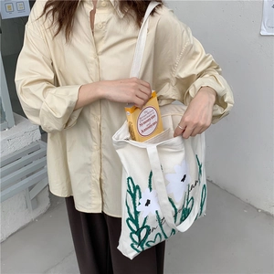 Detail showing a minimalist chamomile canvas tote bag being filled with books