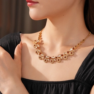Close-up of vintage gold necklace with ruby red and clear crystals on a model