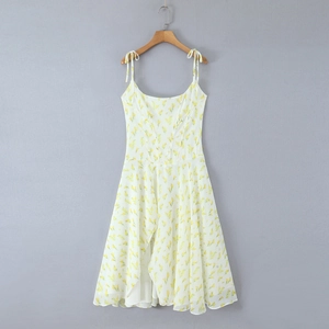 Dettaglio di un abito in chiffon bianco con motivi floreali gialli e spalline annodate
