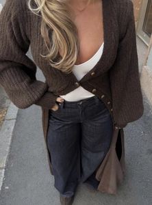 Texture détaillée du tricot d'un long cardigan marron avec poignets côtelés