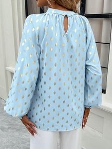 Detail of light blue women's blouse with gold leaf print and back cutout button design