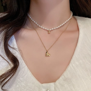 Close-up of elegant double-layer necklace with pearl beads and gold heart pendant on model