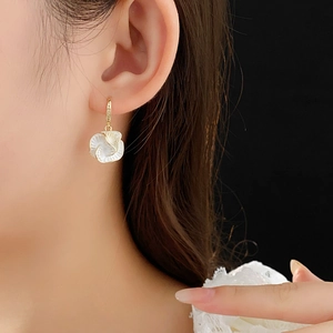 Close-up of a model wearing vintage gold plated floral earrings with shell petals