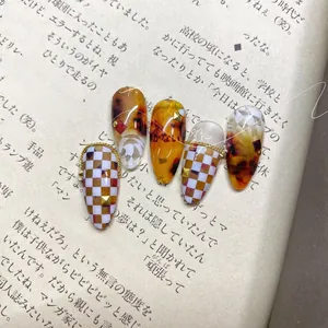 Detailed view of amber nails with checkerboard pattern and floral hand-painted art