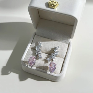 Macro shot of silver stud earrings with pink pear-cut gemstones in a white gift box