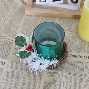Détail du bougeoir en verre vert avec baies rouges et feuilles de houx sur papier rétro