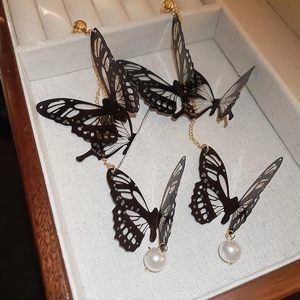 Vue détaillée de boucles d'oreilles papillon noires avec perles dans un écrin à bijoux