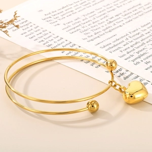 Detail shot of 18K gold-plated heart pendant bracelet on vintage book background