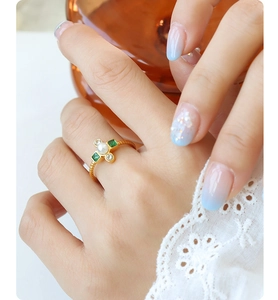 Detail of gold-plated spiral ring with green gems, zircons and a central pearl