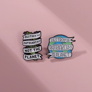 Enamel badges with Destroy The Patriarchy Not The Planet slogan on pink background