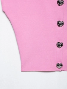 Dettaglio del top rosa in maglia con bottoni metallici a forma di cuore dal design fluido
