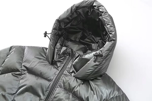 Detail of hood with drawstring and metal zipper on black padded winter jacket