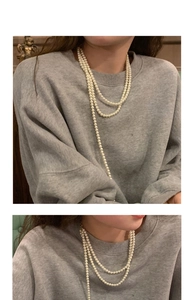 Detail of layered white pearl necklace worn over a grey sweatshirt for a vintage look