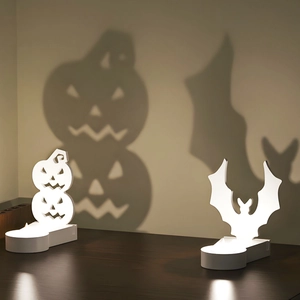 Halloween pumpkin and bat silhouette candle holder set casting shadows on a wall