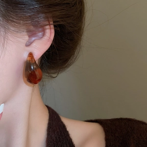 Close-up of translucent amber resin teardrop earrings worn on model for vintage style