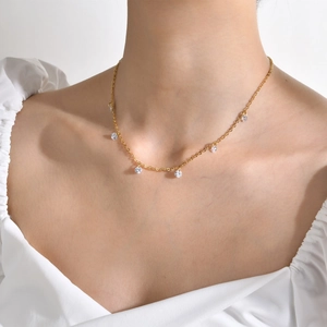 Close-up of golden necklace with sparkling clear zircon pendants worn on a female neck