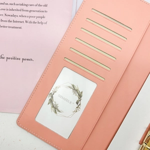 Detail of coral pink leather notebook interior with card slots and a clear ID window