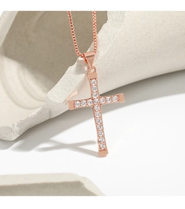 Macro shot of rose gold cross pendant with clear cubic zirconia stones on box chain