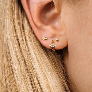 Close-up of gold S925 sterling silver star charm earrings with sparkling zircons on ear