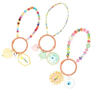 Detail of colorful beaded keychains with flower, heart and evil eye charms on white background