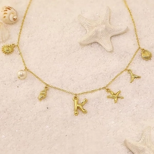 Gold bohemian ocean necklace with shell and starfish pendants on a sandy beach
