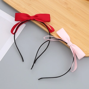 Red and pink bow headbands for girls on a wooden board with minimalist black thin bands