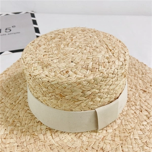 Detail of hand-woven raffia straw hat with elegant beige ribbon on white background
