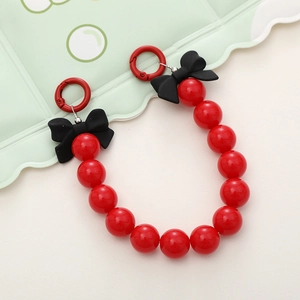 Detail of red acrylic beaded phone strap featuring a black 3D bow and red round hook