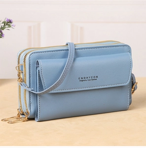 Detail view of the light blue crossbody bag with double gold zippers and leather texture