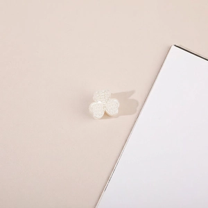 Detailed close-up of a white clover hair clip with pearl texture and beaded surface