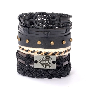 Set of five multilayered leather bracelets with rudder and heart charms on white background