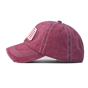 Detail of vintage washed cotton baseball cap with distressed flag embroidery in burgundy