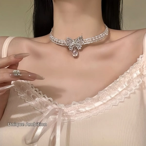Detail of elegant bow choker with rhinestones and pearl pendant on model's neck