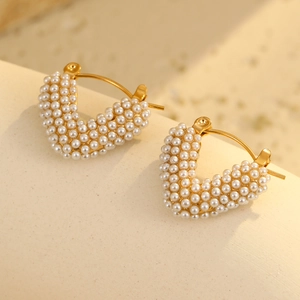 Macro detail of 18K gold-plated heart hoop earrings featuring white pearl inlay accents