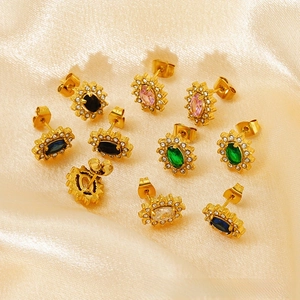 Close-up of geometric sunflower stud earrings with colorful zircons on champagne silk