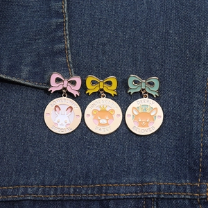 Close-up of enamel pins with cute bear, rabbit, and deer charms on denim fabric