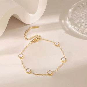 Golden stainless steel jewelry set with white round pearls on elegant beige background