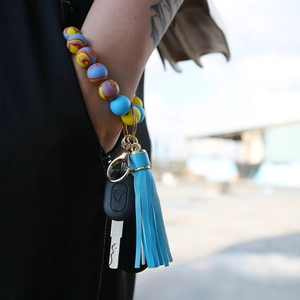 Detail of colorful silicone beaded bracelet keychain with blue leather tassel on wrist