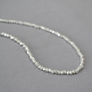 Macro shot of silver plated irregular faceted beads on minimalist brass necklace chain