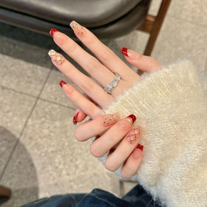 Close-up of red French tip press-on nails with plaid patterns and gold accents