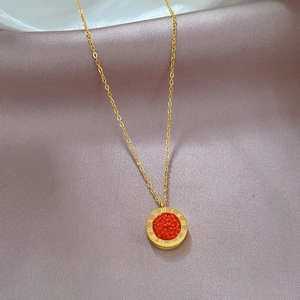Detailed close-up of golden titanium necklace with red Roman numeral pendant on satin