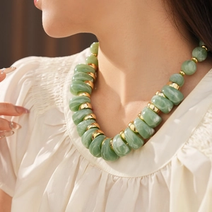 Vue détaillée d'un collier vintage avec perles en résine verte et anneaux dorés