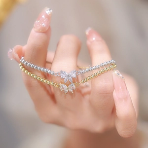 Close-up of elegant gold and silver beaded bracelets with sparkling butterfly cubic zirconia