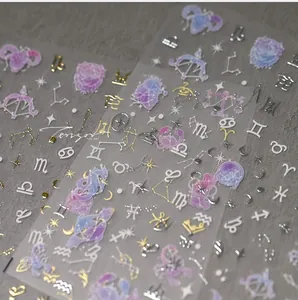 Detail of zodiac nail stickers featuring gold and silver constellation symbols and moons